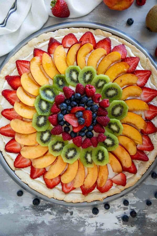 Fruit pizza consisting of a sugar cookie base topped with cream cheese frosting and fresh fruit.