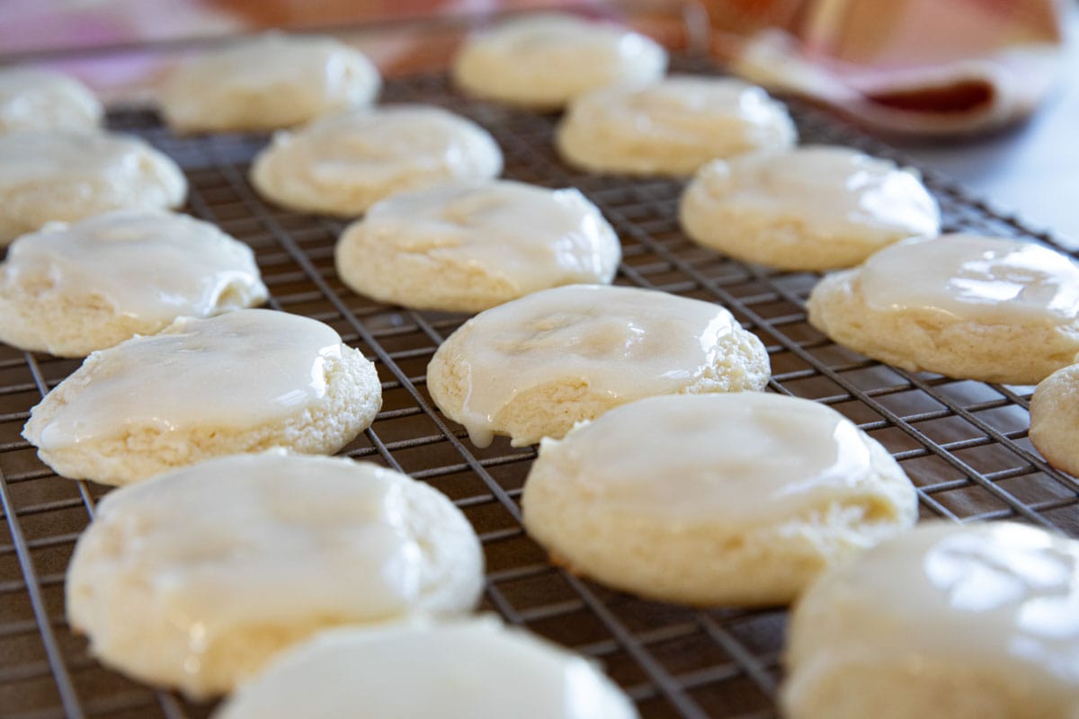 Sour cream cookies topped with sour cream glaze on a cooling rack.