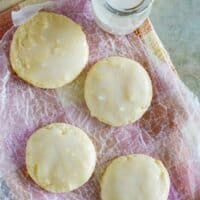 Sour cream cookies on wrinkled paper with a jar of milk next to the cookies.