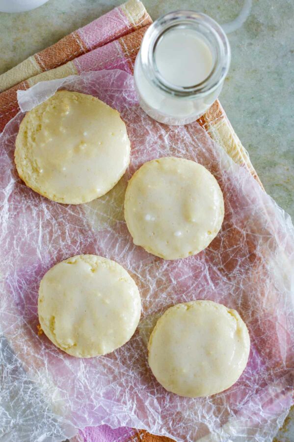 Sour cream cookies on wrinkled paper with a jar of milk next to the cookies.