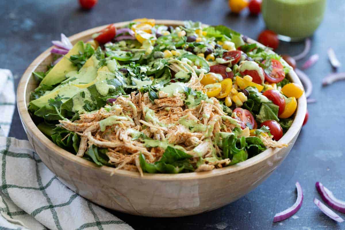 Bowl filled with Southwest Chicken Salad - a salad with taco seasoned chicken, lettuce, tomatoes, beans, corn, and more.