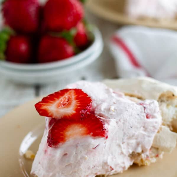 Slice of strawberry cream angel pie on a plate.