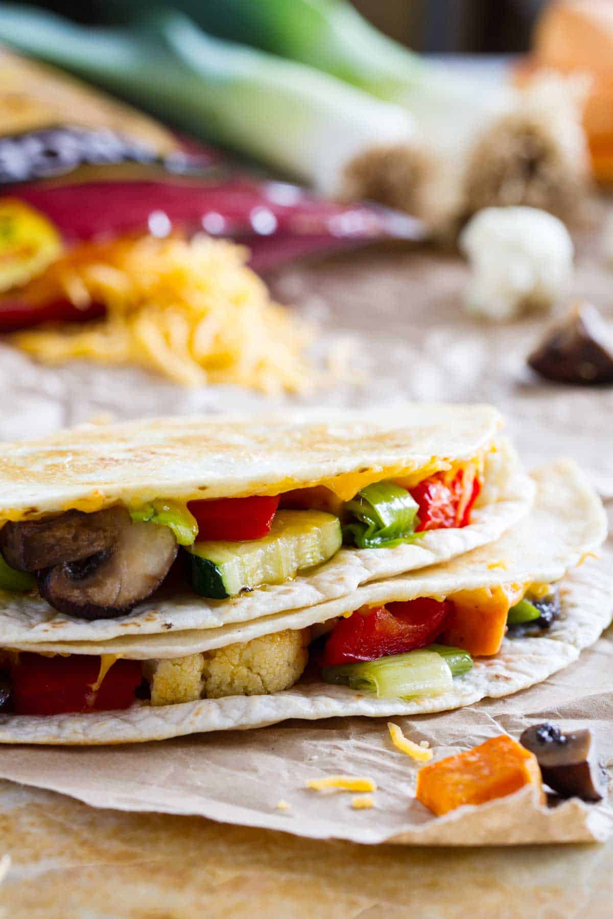 A great way to get your veggies in, this Veggie Quesadilla is a great way to clean out the veggie drawer to make a lunch or dinner that won’t leave you missing the meat! Slices of a veggie quesadilla stacked on top of each other.