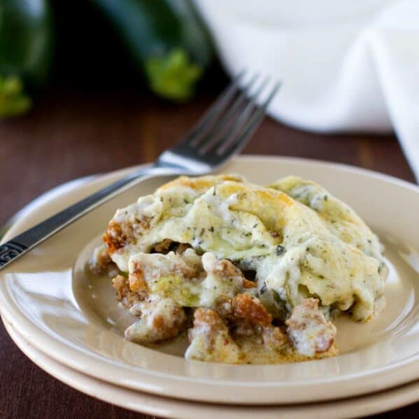 Serving of zucchini sausage casserole on a plate with a fork.