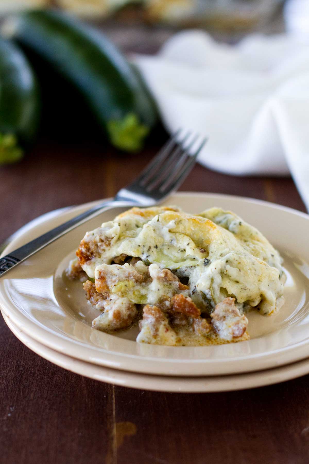 Serving of zucchini sausage casserole on a plate with a fork.