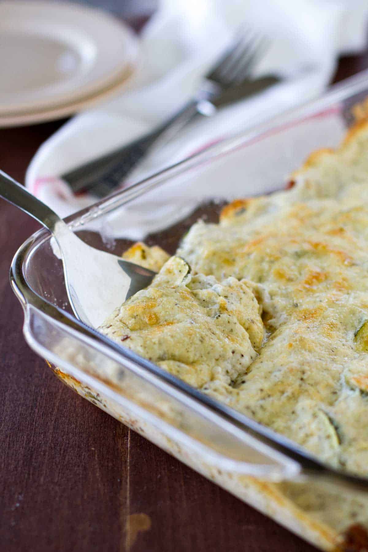 Zucchini Sausage Casserole in a dish with a spoon for serving.