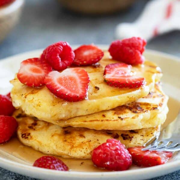 Stack of cottage cheese pancakes topped with syrup and berries.