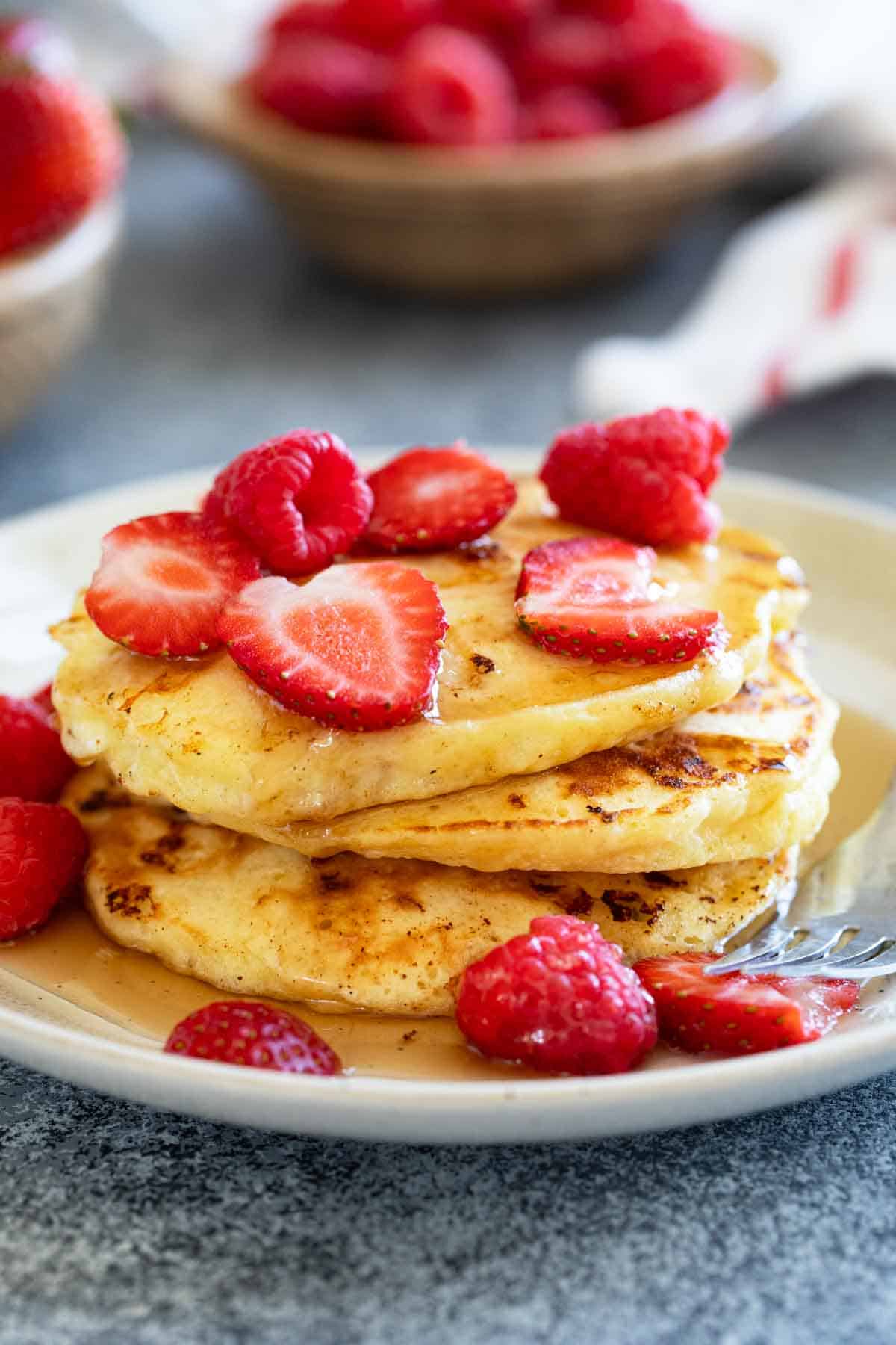 Stack of cottage cheese pancakes topped with syrup and berries.