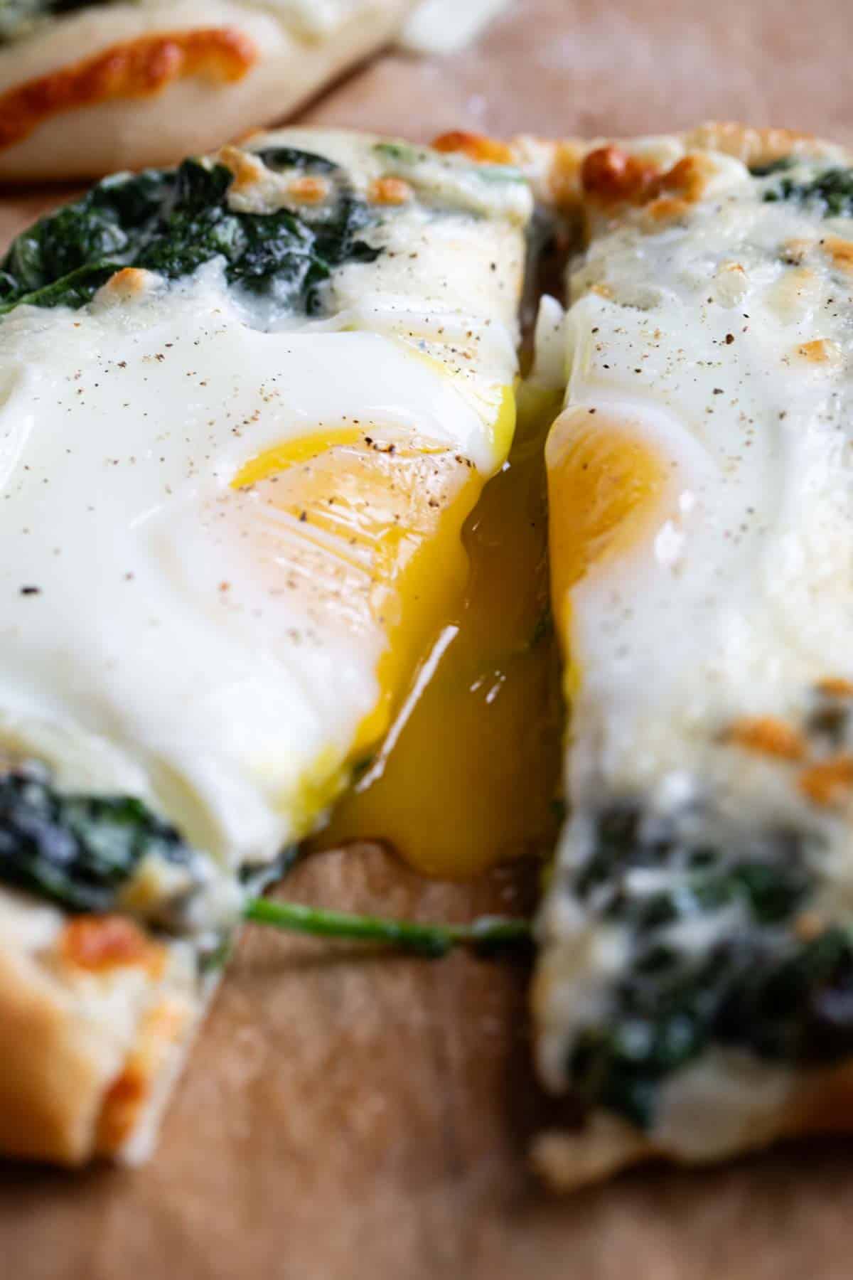Egg pizza cut in half with egg yolk dripping.