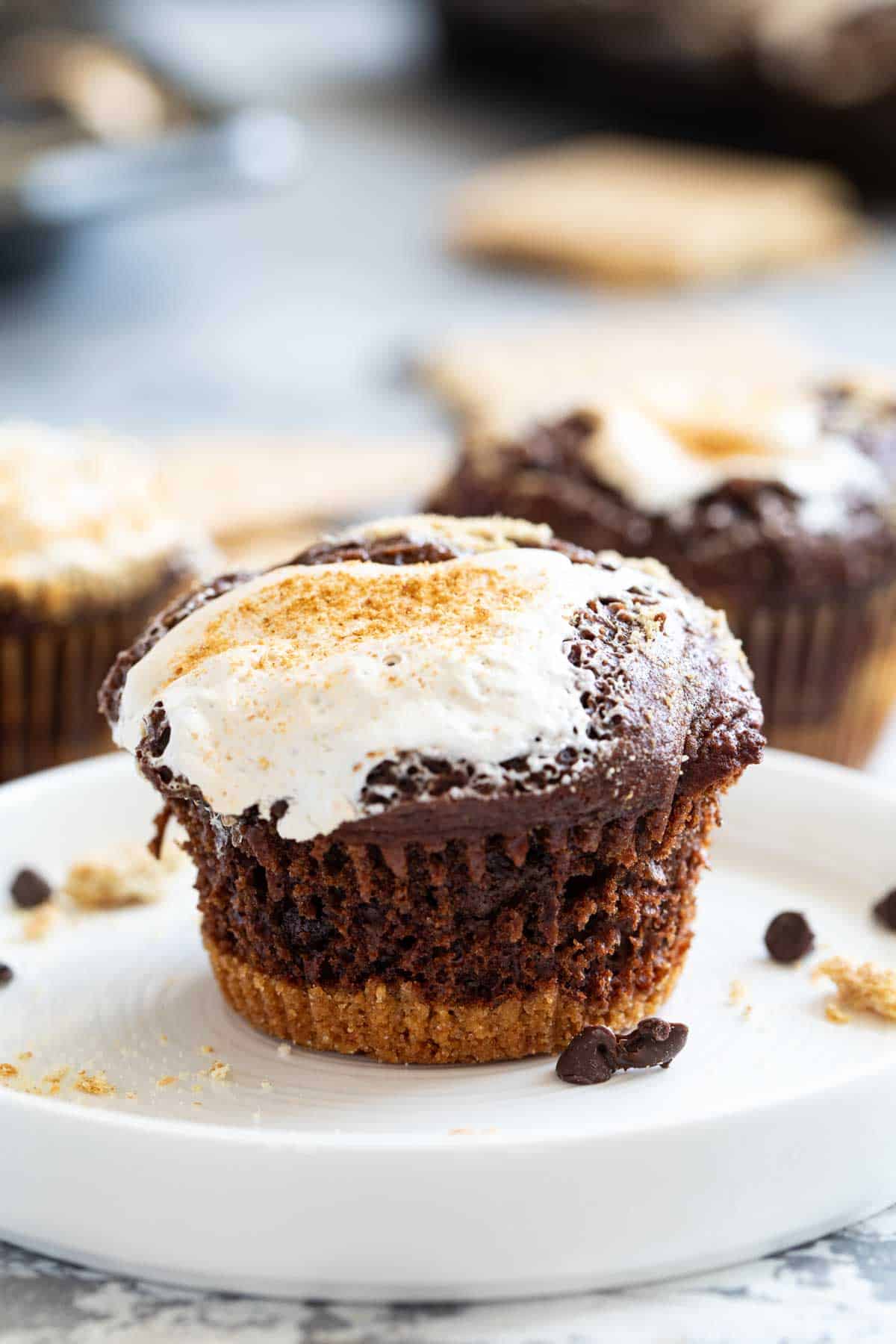 S'mores muffin on a plate, topped with marshmallow and graham cracker crumbs.