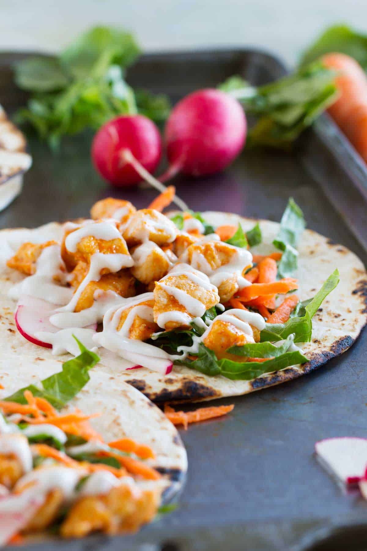 Tortillas filled with buffalo chicken and taco toppings.