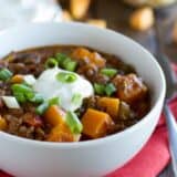 Bowl of butternut squash chili with ground beef topped with sour cream.
