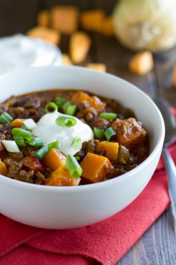 Bowl of butternut squash chili with ground beef topped with sour cream.