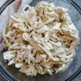 Chicken salad with celery and red onions in a glass bowl.