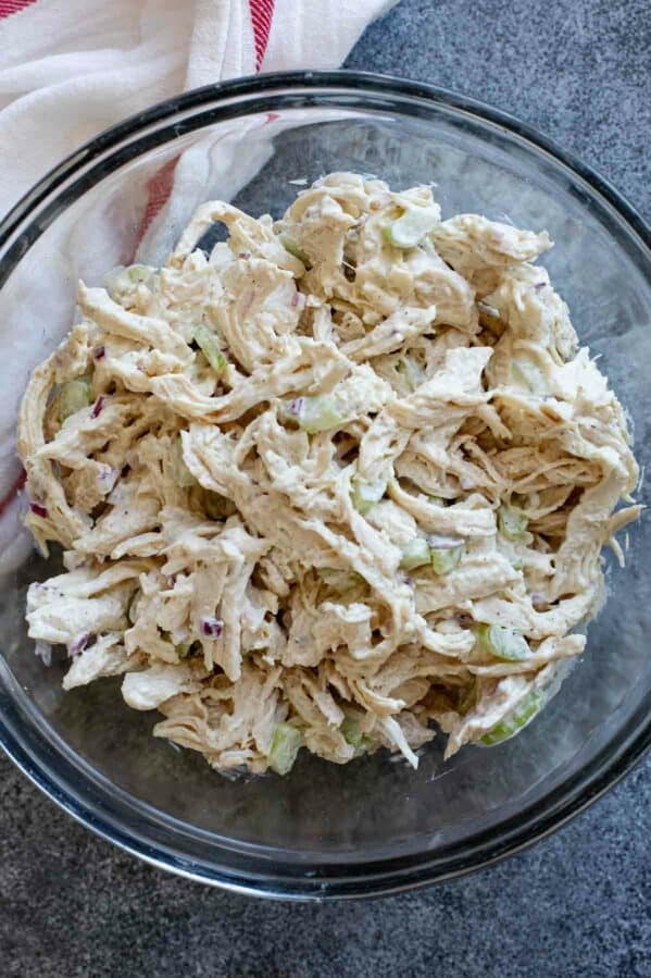 Chicken salad with celery and red onions in a glass bowl.