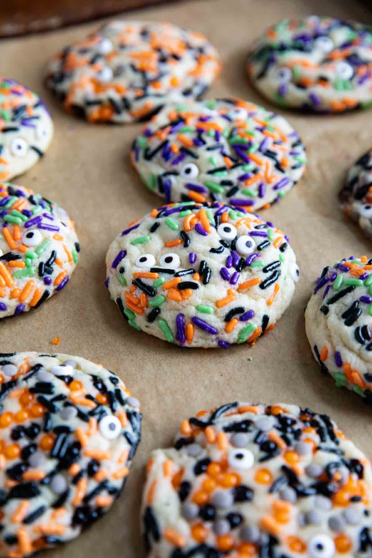 Halloween cookies with different sprinkles on a baking sheet.