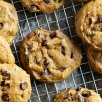 Pumpkin Chocolate Chip Cookies stacked on a cooling rack.