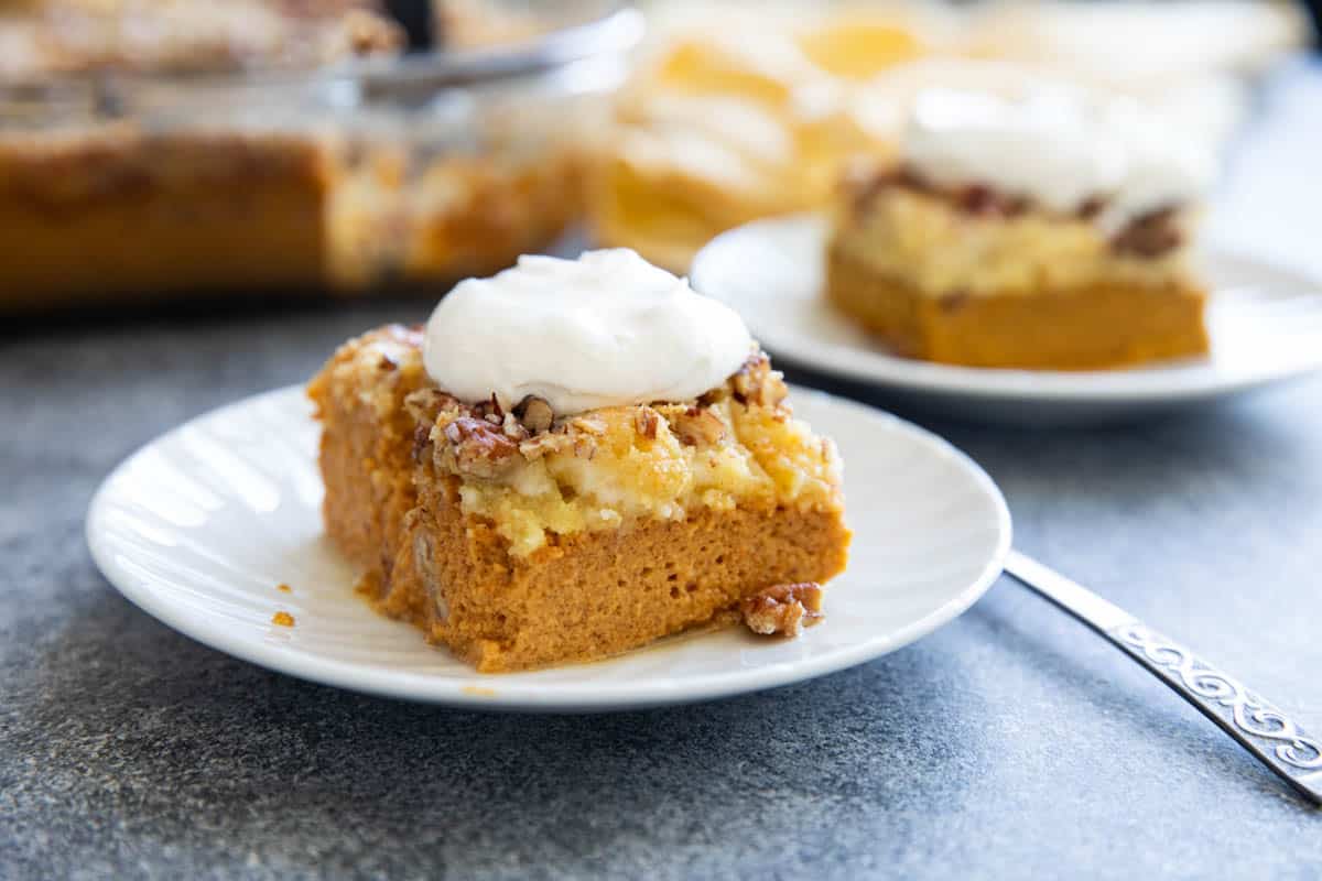 Pumpkin Dump Cake on a plate, topped with fresh whipped cream.