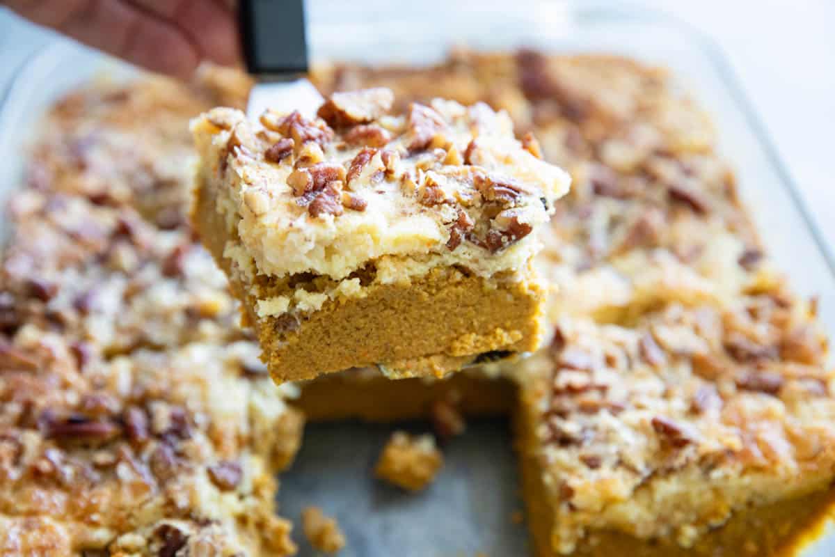 Slice of pumpkin dump cake being taken out of the baking pan.