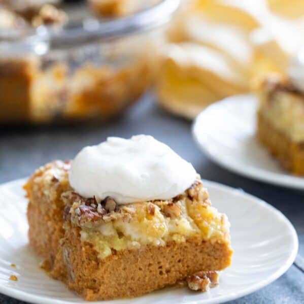 Slice of pumpkin dump cake with pecans, topped with whipped cream.