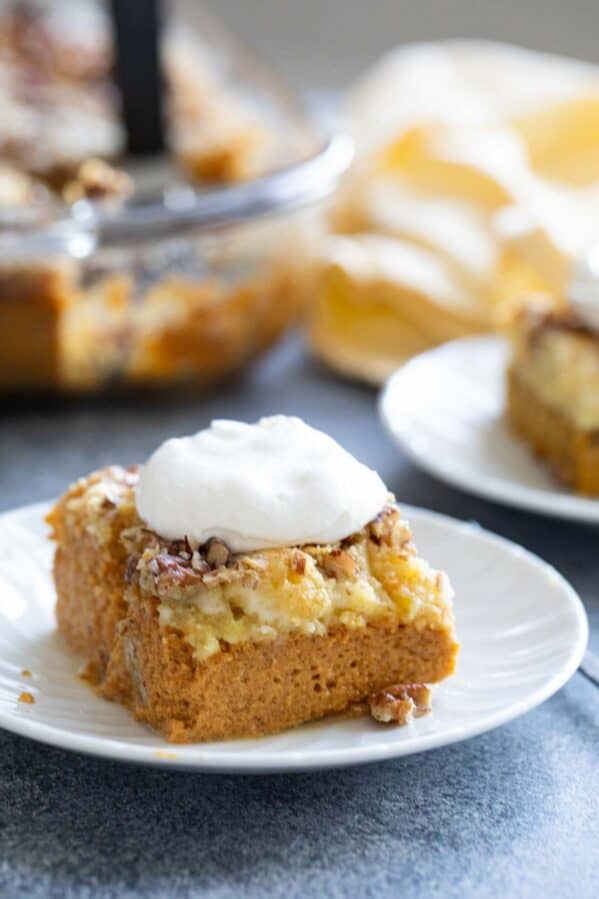 Slice of pumpkin dump cake with pecans, topped with whipped cream.