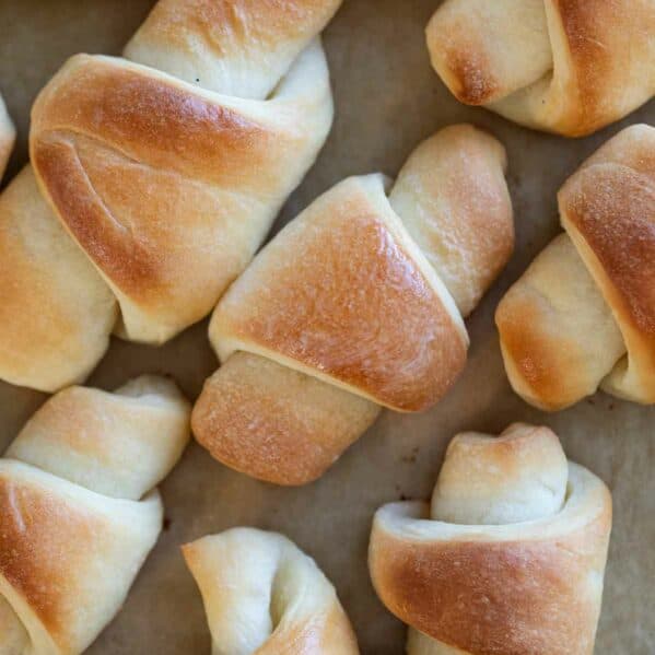 Multiple butterhorn rolls on a sheet of parchment paper.