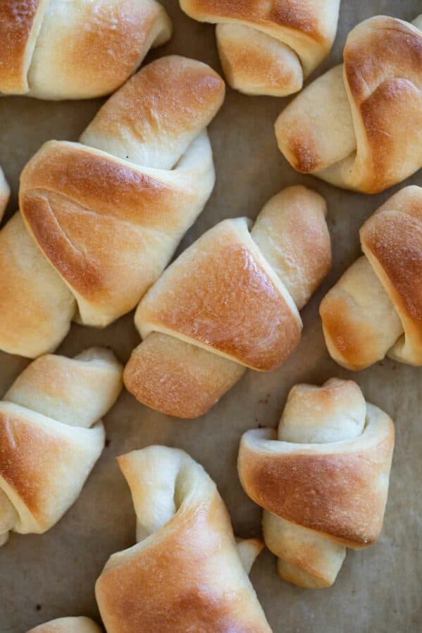 Multiple butterhorn rolls on a sheet of parchment paper.