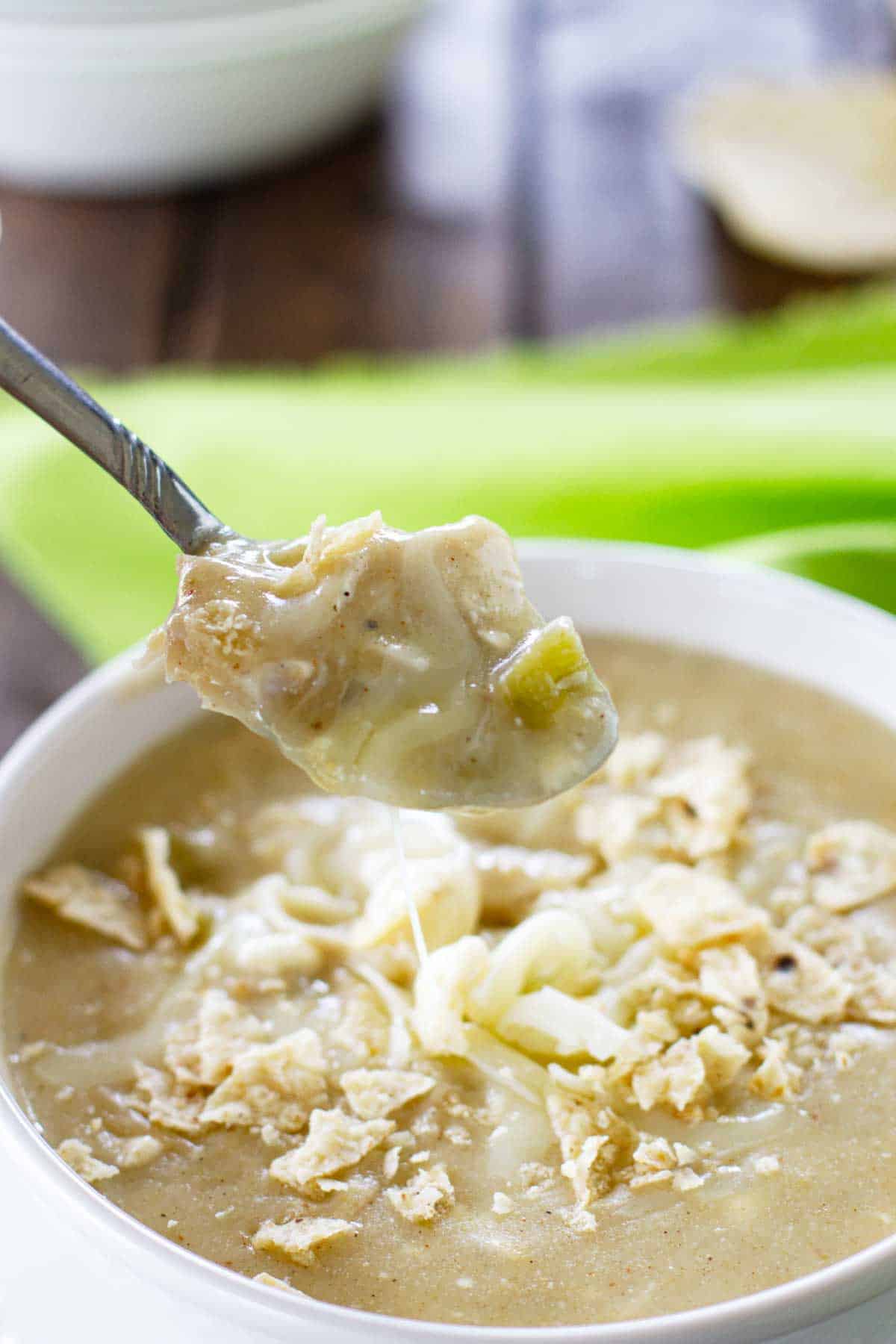 Bowl of green chicken enchilada soup with a spoonful of the soup.