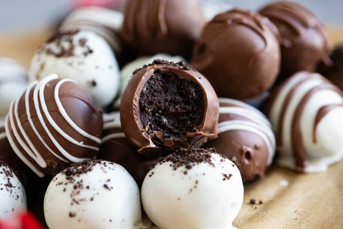 Oreo balls in milk chocolate and white chocolate with a bite taken from one truffle.