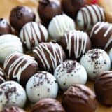 Oreo truffles in white chocolate and milk chocolate lined up on parchment paper.