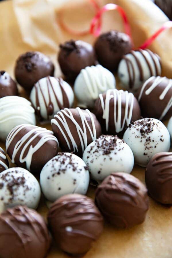 Oreo truffles in white chocolate and milk chocolate lined up on parchment paper.