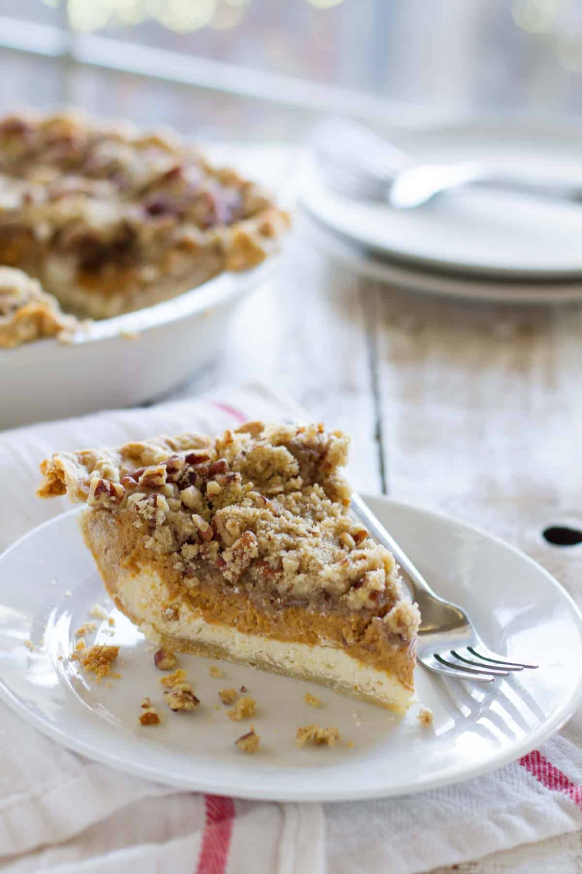 Slice of pumpkin cheesecake pie on a plate with the full pie behind it.