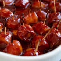 Bacon Wrapped Water Chestnuts covered in a homemade bbq sauce in a baking dish.