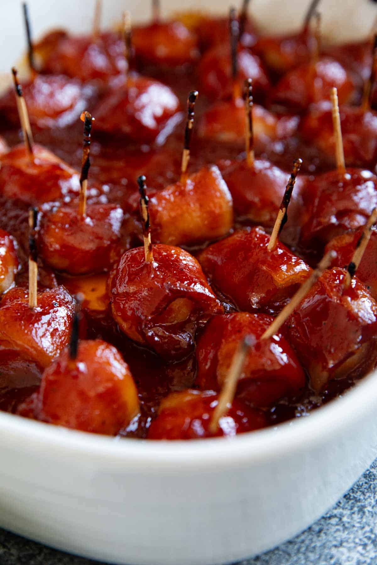 Bacon Wrapped Water Chestnuts covered in a homemade bbq sauce in a baking dish.