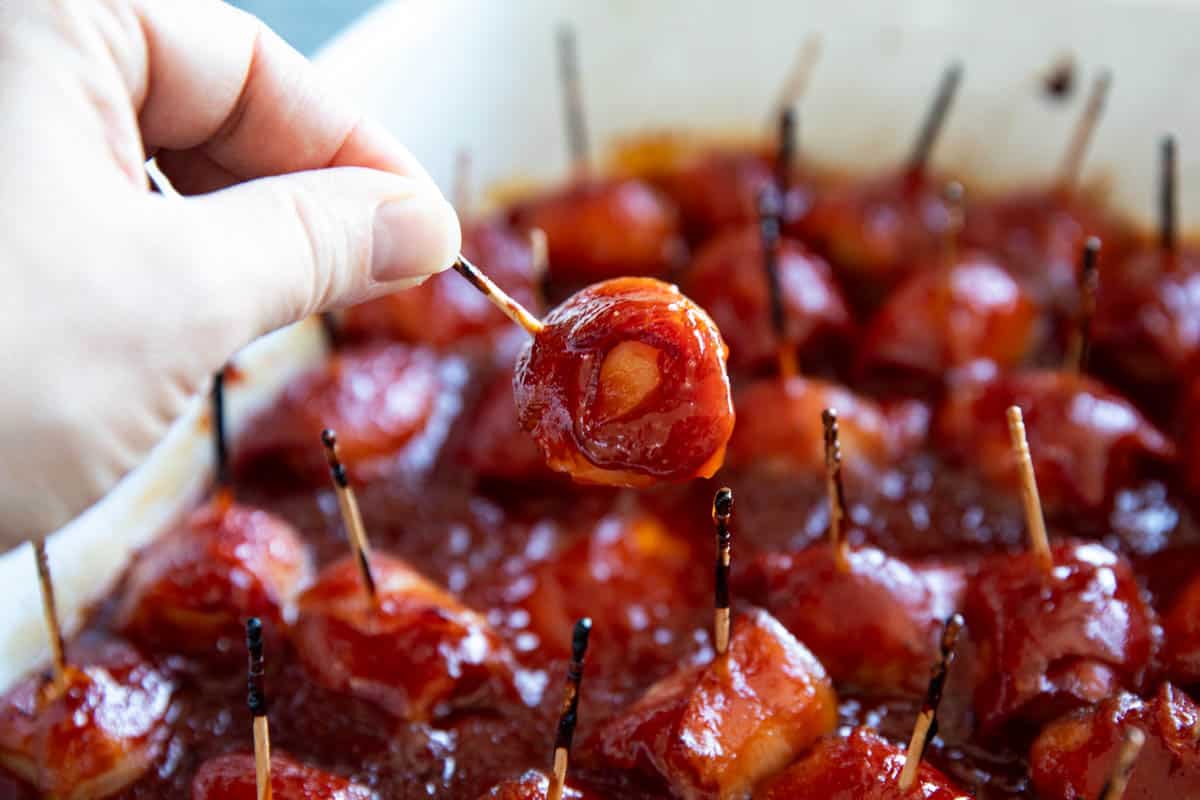 Bacon wrapped water chestnut on a toothpick being held.