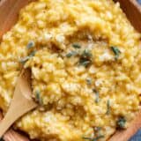 Butternut squash risotto topped with sage in a wooden bowl.