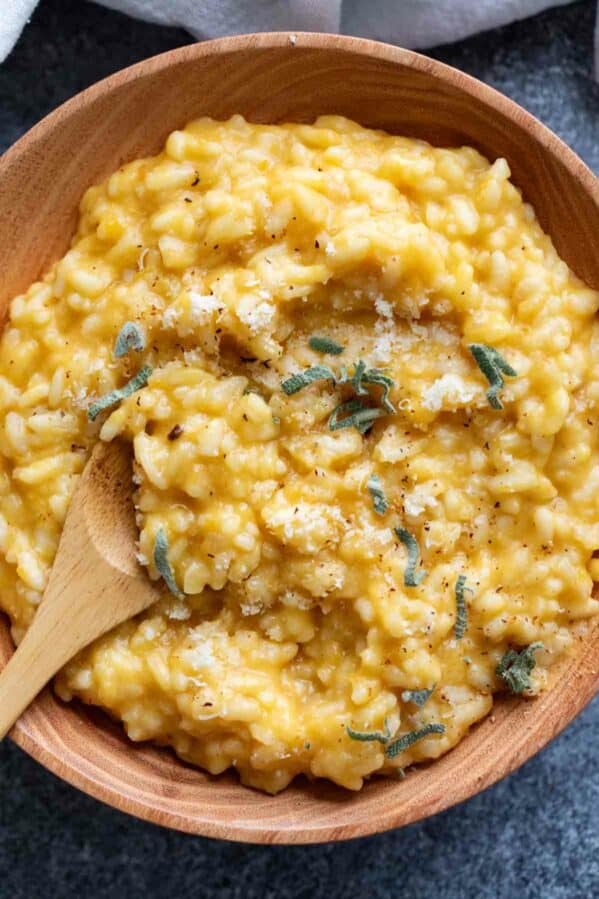 Butternut squash risotto topped with sage in a wooden bowl.