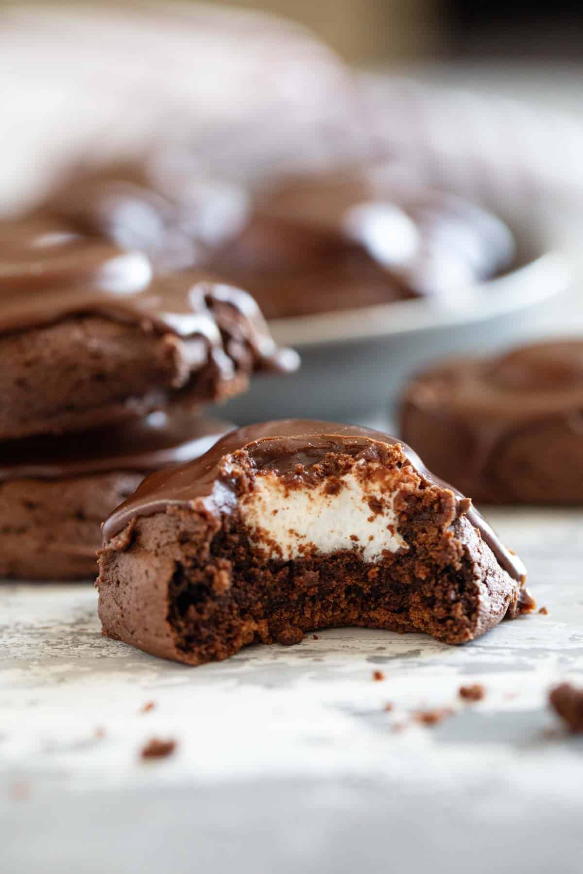 Chocolate marshmallow cookie with a bite taken out to show marshmallow in the center.