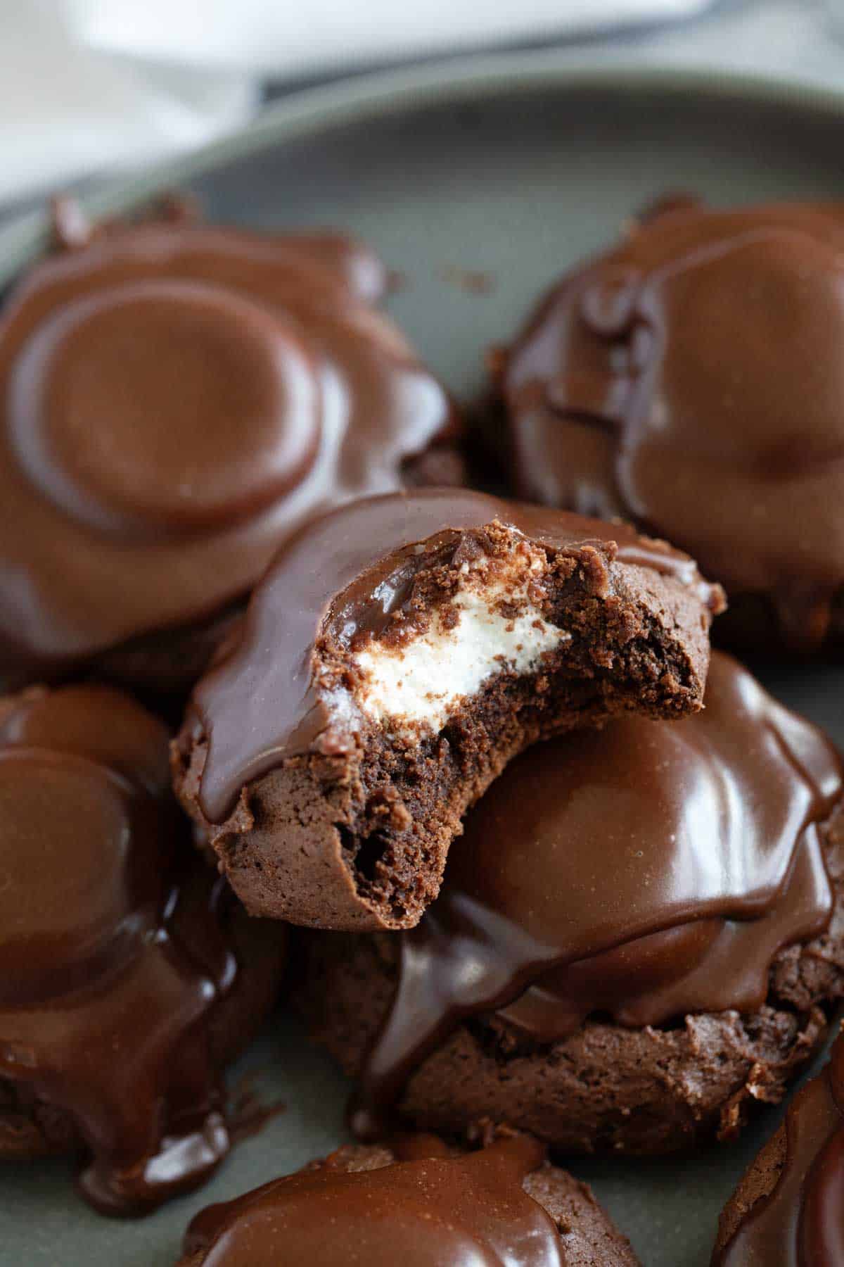 Plate full of chocolate marshmallow cookies with a bite taken out of one cookie.