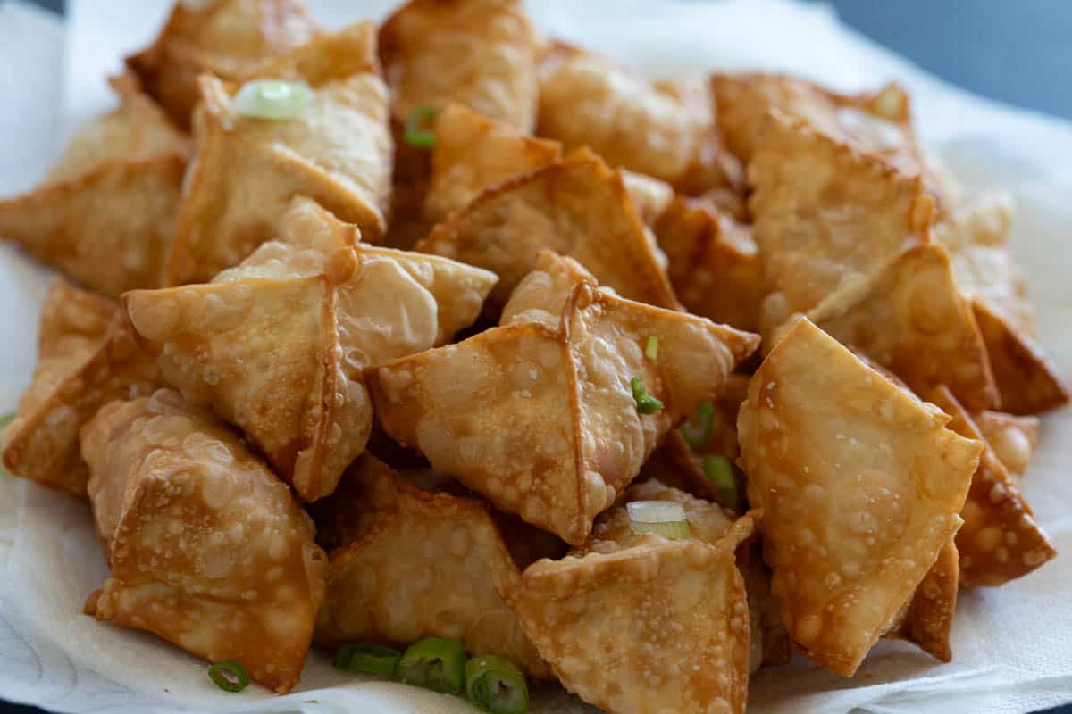 Crab Rangoon on a plate with green onions.