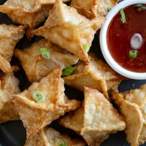 Plate filled with crab rangoon with a bowl of sweet chili sauce.