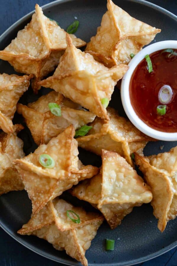 Plate filled with crab rangoon with a bowl of sweet chili sauce.
