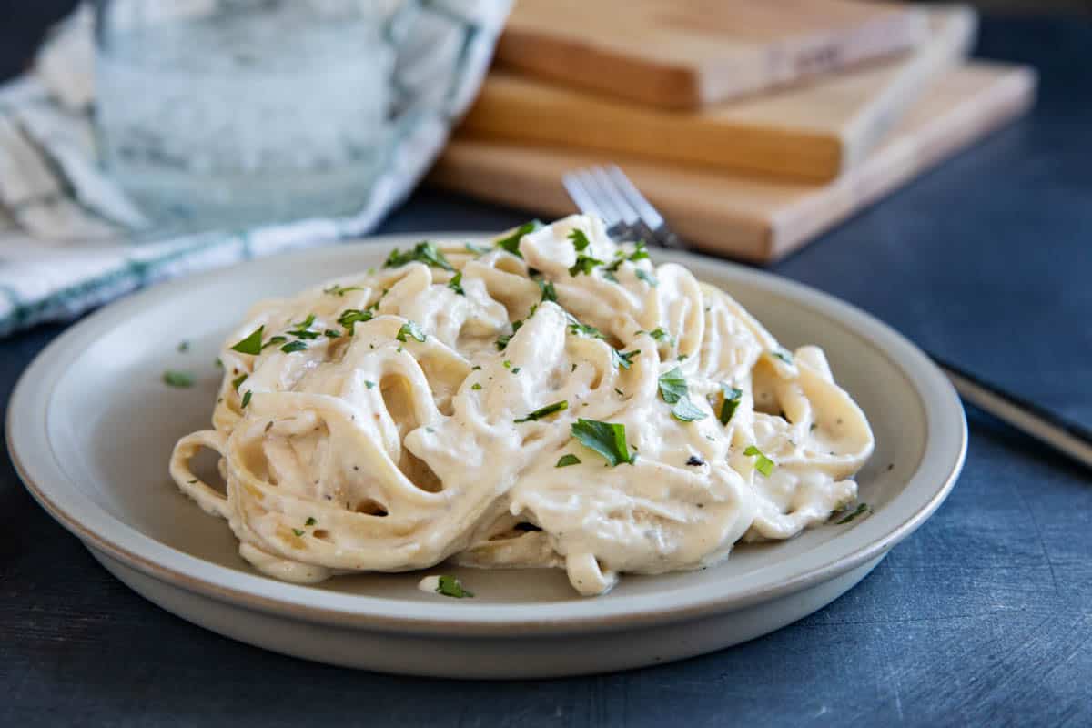 Plate with crock pot chicken alfredo - shredded chicken in a creamy alfredo sauce with fettuccine noodles.