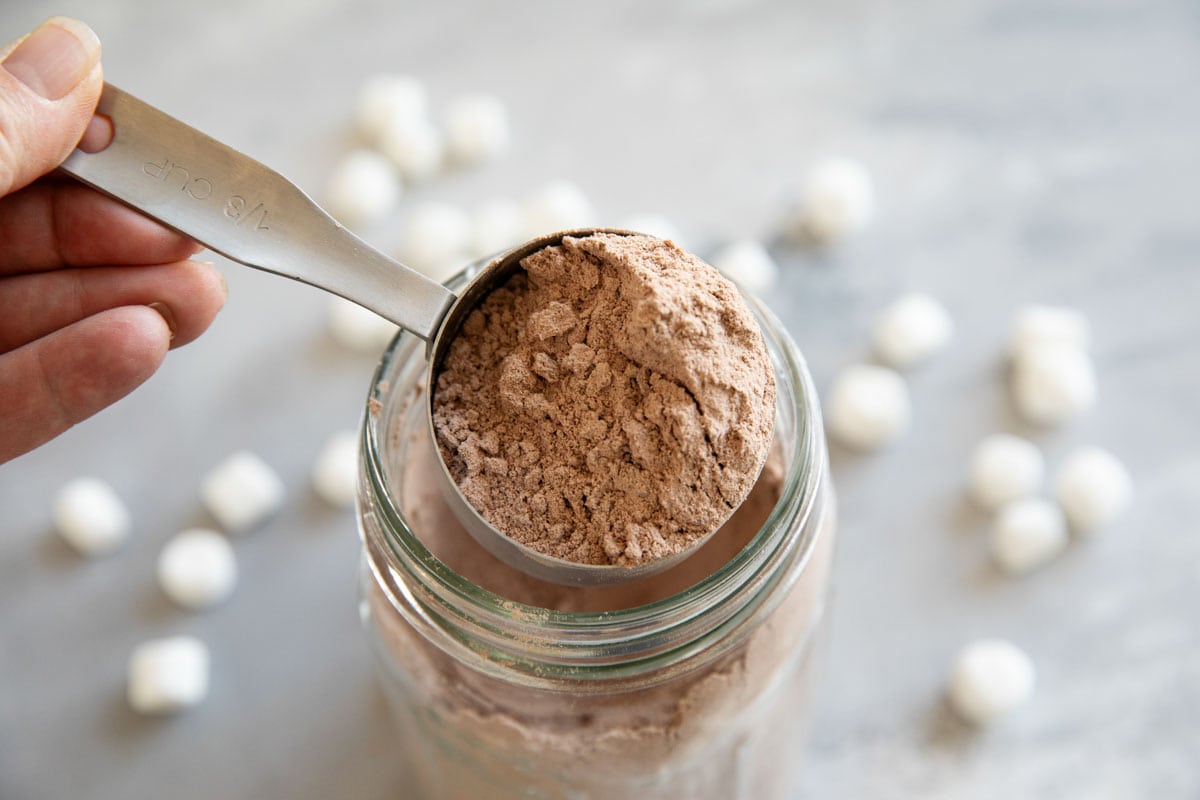 Homemade hot chocolate mix in a jar with a measuring cup.