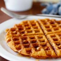 Maple Bacon Waffle on a plate, with syrup drizzled over the top of the waffle.