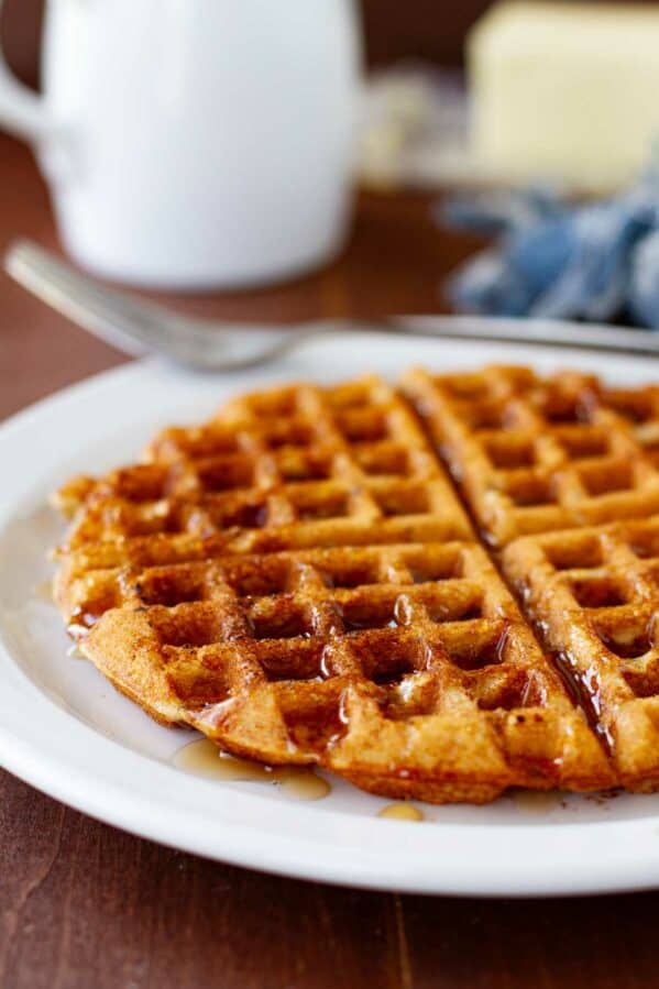 Maple Bacon Waffle on a plate, with syrup drizzled over the top of the waffle.