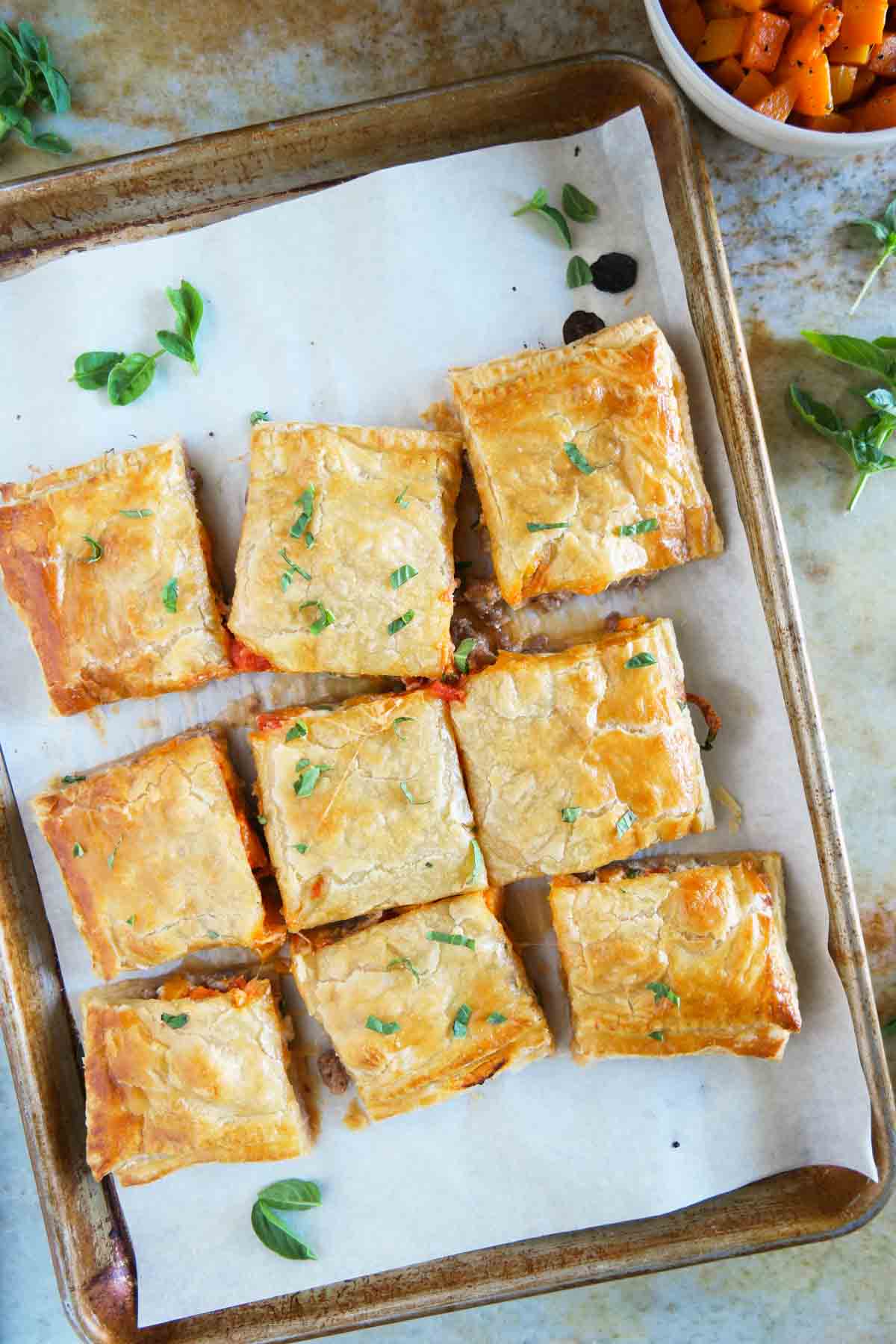 Sausage and Butternut Squash Slab Pie sliced into squares on a baking sheet.