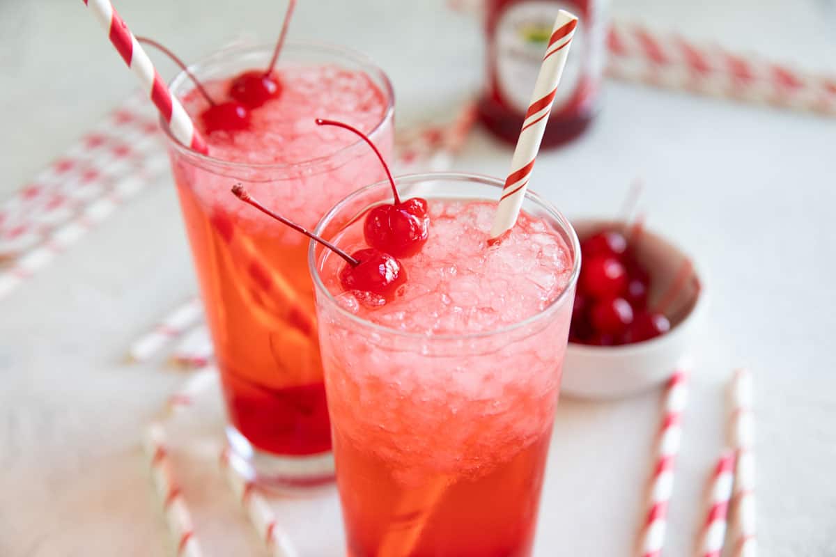 Glasses filled with Shirley temple drinks with red and white straws.