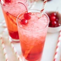 Glasses of Shirley temples topped with maraschino cherries.