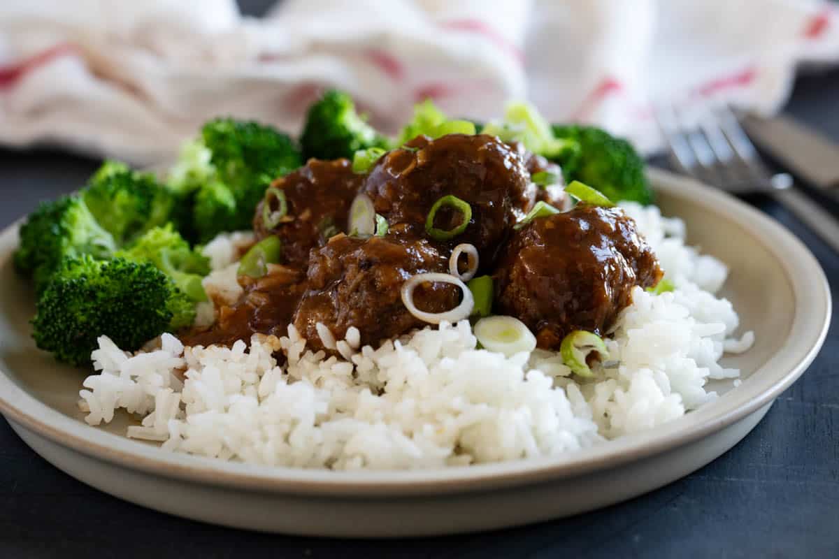 Slow cooker Asian meatballs with rice and green onions.